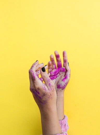 hands covered in paint against a yellow background