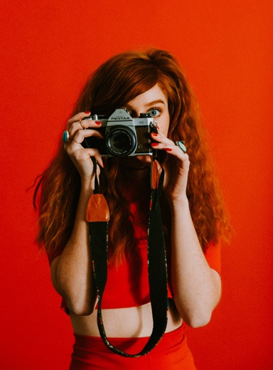 girl with camera against a red background